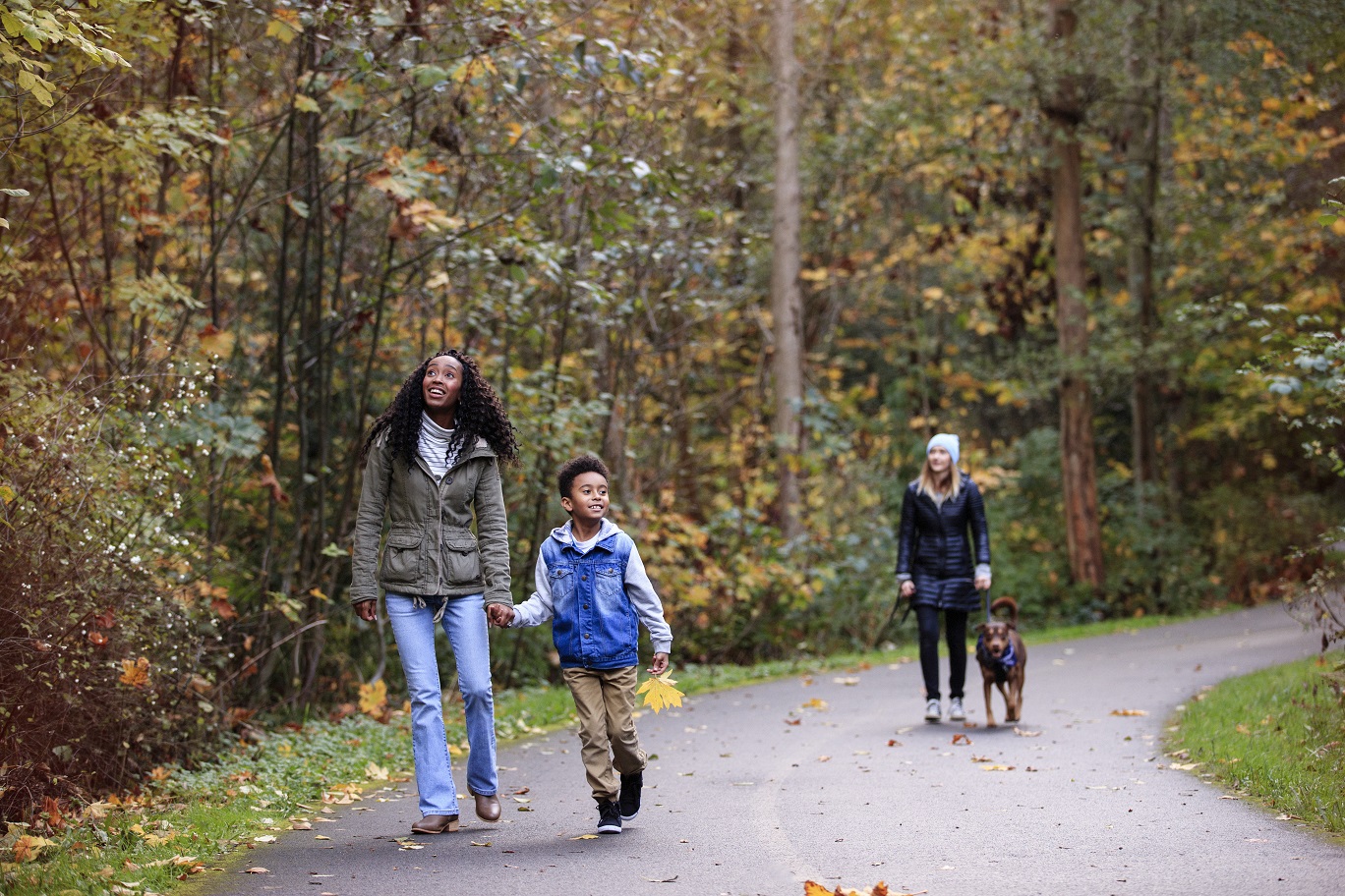 Mother and son walking on a trail with falling leaves